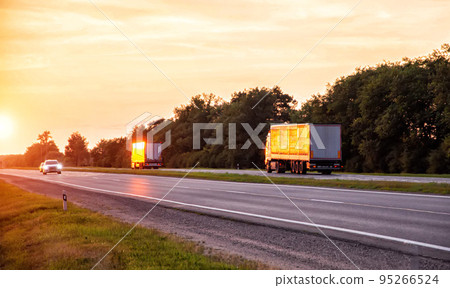 a convoy of trucks delivers cargo along the highway in the evening at sunset. The concept of cargo transportation and logistics companies FTL 95266524