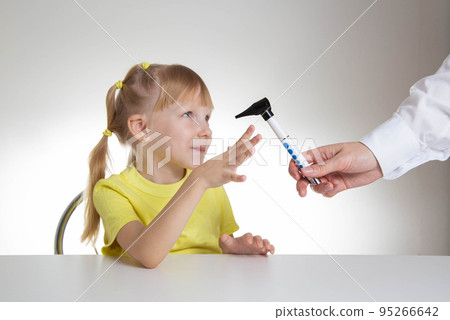 The doctor examines the ear canal of a little caucasian girl 5 years old in the doctor's office. Diagnosis and treatment of ear diseases, close-up 95266642