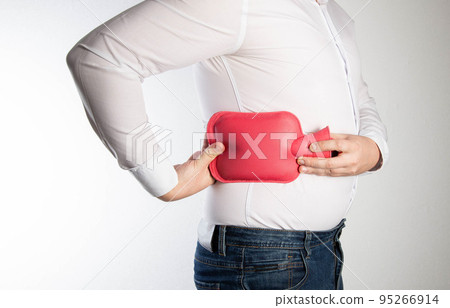 A man holds a red heating pad with water near the side of his back. The concept of treatment of sprains, hypothermia of muscles and ligaments. Thermotherapy A man holds a red heating pad with water near the side of his back. The concept of treatment of sprains, hypothermia of muscles and ligaments. Thermotherapy 95266914