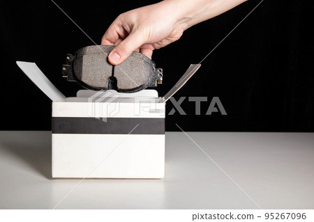 The mechanic takes out new car brake pads to replace them. Black background, copy space for text The mechanic takes out new car brake pads to replace them. Black background, copy space for text 95267096