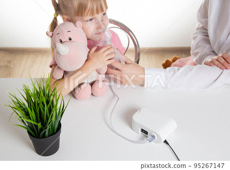 A 5-year-old girl breathes into an inhaler to dilute sputum in case of lung diseases. Treatment of cough in children. Nebulizer therapy 95267147