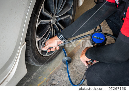 Expert mechanic checks tire pressure with nitrogen and has a pressure gauge. 95267168