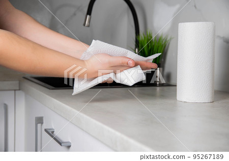 A man wipes his hands with a paper towel in the kitchen. Napkins for care. Copy space for text 95267189