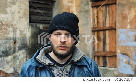 Portrait of bearded homeless. Male refugee needs help. Tramp in dirty clothes and hat, cap. Below poverty line. Fugitive beggar. Illegal immigrant. Consequences of drunkenness, alcoholism 95267197