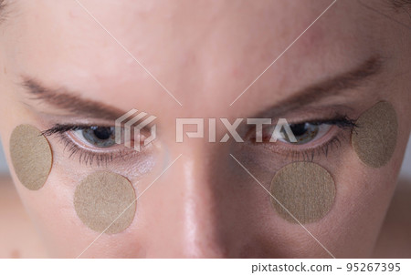 Medical medical plaster for relieving fatigue and tension from the eyes of a girl, macro Medical medical plaster for relieving fatigue and tension from the eyes of a girl, macro 95267395