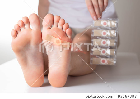 The girl holds in her hand a set of medical plasters for plantar warts. Treatment of calluses on the feet 95267398