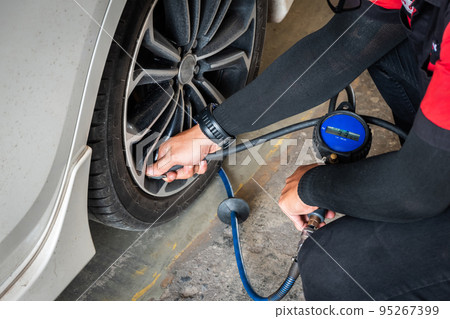 Expert mechanic checks tire pressure with nitrogen and has a pressure gauge. Expert mechanic checks tire pressure with nitrogen and has a pressure gauge. 95267399