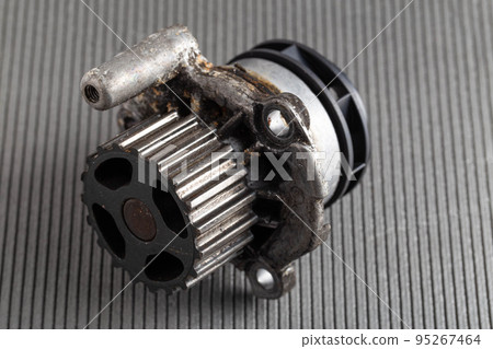 Old car pump on a gray background. The concept of repair and replacement of the pump. Automotive spare part from the cooling system, close-up Old car pump on a gray background. The concept of repair and replacement of the pump. Automotive spare part from the cooling system, close-up 95267464