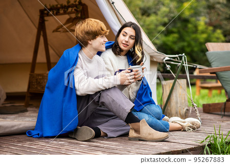 A couple sitting near a tent at glamping A couple sitting near a tent at glamping 95267883