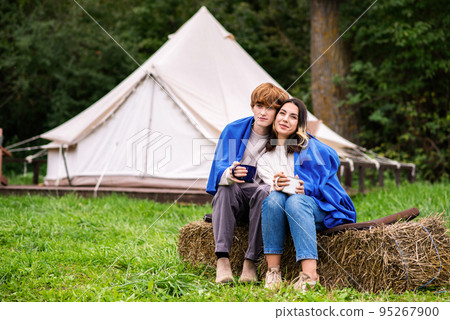 A couple sitting near a tent at glamping A couple sitting near a tent at glamping 95267900