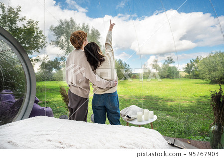 A couple inside a transparent bubble tent at glamping A couple inside a transparent bubble tent at glamping 95267903