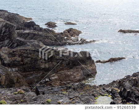 Exposed rocks on the shore. Seaside rocks in sunny weather, rock formation near body of water. 95268539