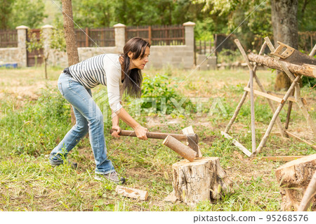 Fit woman chopping a log on a garden Fit woman chopping a log on a garden 95268576