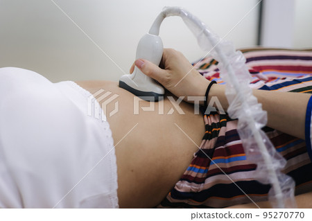 Doctor giving patient an ultrasound. Young woman getting pancreas control in moder clinic 95270770