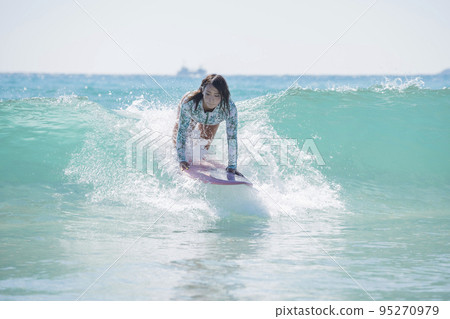 A young woman surfing in the sea, the moment of takeoff, a surfing girl, a surfing girl 95270979