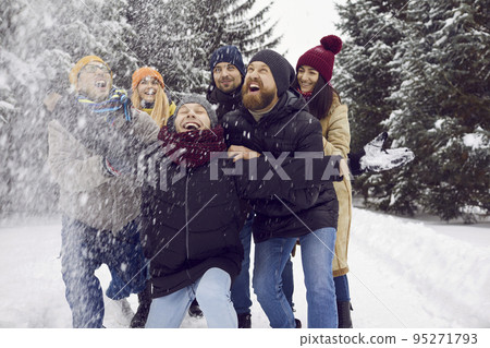Group of happy young friends walking in a winter forest, having fun in the snow and laughing 95271793