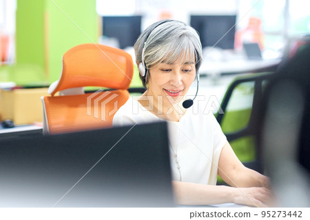 A veteran female operator wearing a headset in the office 95273442