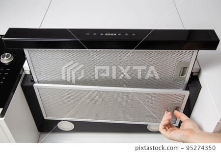 Replacing the charcoal filter that eliminates odors in the kitchen in the hood. Close-up 95274350