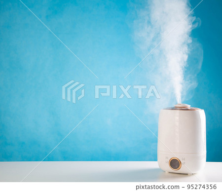 Modern device for air humidification on a blue background. Wet Steam Humidifier. Copy space for text Modern device for air humidification on a blue background. Wet Steam Humidifier. Copy space for text 95274356