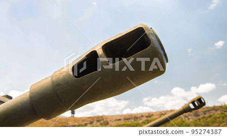 The green muzzle of a tank against the blue sky. The concept of military conflicts and children, war. Copy space for text The green muzzle of a tank against the blue sky. The concept of military conflicts and children, war. Copy space for text 95274387