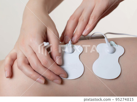 Electrodes of modern acupuncture and anti-cellulite massagers on the legs of a girl in problem areas. Home physiotherapy, close-up 95274815