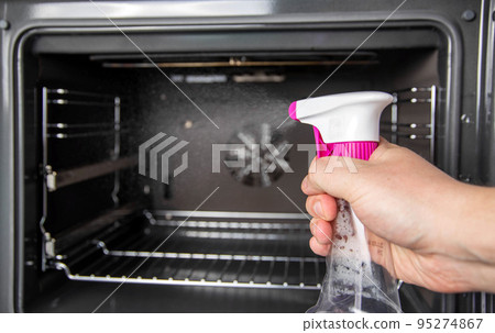 Spraying the cleaning agent inside the oven to clean it. Caring for modern electric ovens, pollution Spraying the cleaning agent inside the oven to clean it. Caring for modern electric ovens, pollution 95274867