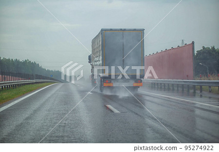 Semi-trailer truck driving on the highway with other cars during heavy rain in summer, wet road. Traffic on the road, keeping the distance, background. Copy space for text 95274922