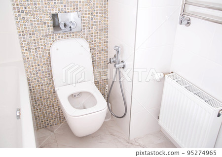 Modern wall-mounted toilet with shower for private spaces. White and clean bathroom 95274965