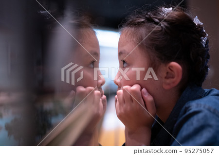 A child seriously looking at something and myself reflected in the glass 95275057