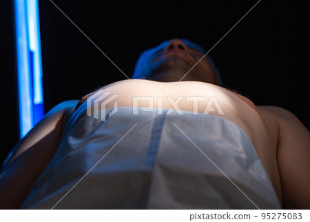 A man on the operating table before undergoing cosmetic gynecomastia surgery. Plastic surgery 95275083