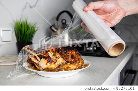 A man wraps a fried chicken in cling film to keep it fresh and smelly. Close-up 95275101