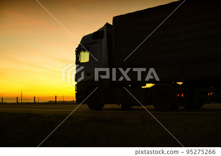 A beautiful truck with a trailer against the backdrop of an evening sunset before night. The concept of work and rest regime for truck drivers. Fine for breaching rules 95275266