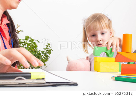 Doctor pediatrician plays toys with a little girl on a medical examination. Copy space for text 95275312