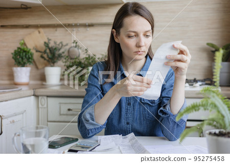 woman pays bills and utilities, counts the amount of expenses and income on a calculator woman pays bills and utilities, counts the amount of expenses and income on a calculator 95275458