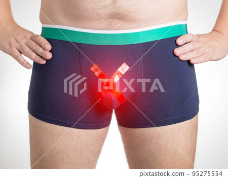 A man in shorts with a red cross. Concept of diseases of the male reproductive system, hydrocele and varicocele. Andrology, close-up 95275554