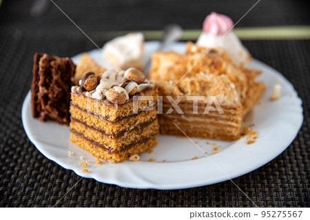 Leftovers in a plate on the table with sweets cakes, close-up 95275567