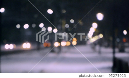 Blurred background. City view, lights, falling snow, night, street, bokeh spots of headlights of moving cars. Diffuse Urban backdrop winter scenery of street in city at night. Lantern light, snowfall Blurred background. City view, lights, falling snow, night, street, bokeh spots of headlights of moving cars. Diffuse Urban backdrop winter scenery of street in city at night. Lantern light, snowfall 95275923