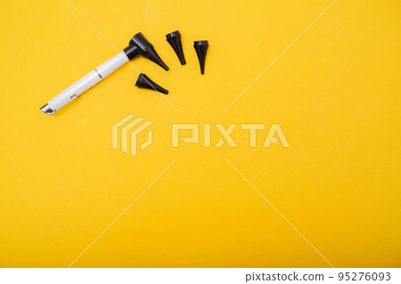 Medical device otoscope on a yellow background. Treatment of ear diseases and diagnostics in the otolaryngolog. Copy space for text 95276093