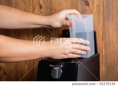 A man inserts a container of water into a coffee maker to make coffee, close-up 95276136