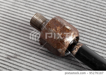 Old rusty steering rod on a gray background, close-up. 95276187