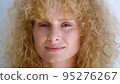 Confident portrait of an attractive charming curly redhead young woman with fresh and radiant skin smiling sweetly looking at the camera. Beautiful diverse people, femininity, human face. Headshot 95276267