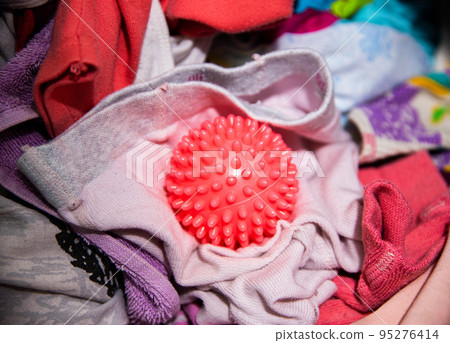 Red ball for washing clothes in the washing machine. Improving the quality of washing, close-up 95276414