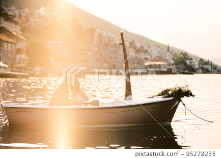 Man and woman are sitting in a boat with oars moored near the shore Man and woman are sitting in a boat with oars moored near the shore 95278235