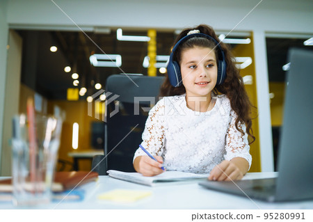 Online education. School girl using laptop computer studying through online e-learning system. Online education. School girl using laptop computer studying through online e-learning system. 95280991