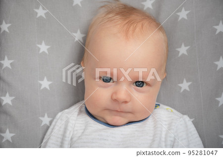 Portrait of serious newborn baby, close-up. Child with blue eyes, looking at camera. Face expression. Portrait of serious newborn baby, close-up. Child with blue eyes, looking at camera. Face expression. 95281047