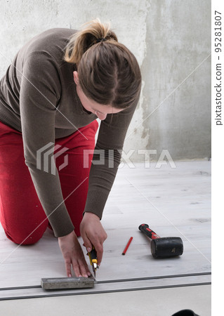 Female master draws a pencil line on a blackboard, installing quartz vinyl flooring. Female master draws a pencil line on a blackboard, installing quartz vinyl flooring. 95281807