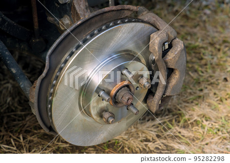 An auto mechanic is replacing brake pads in system automobile at service center 95282298
