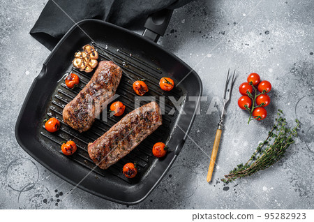 Roasted Lamb tenderloin fillet meat on grill pan, mutton sirloin steak. Gray background. Top view 95282923