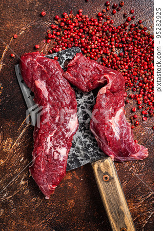 Raw Machete steak and flap steak flank cut on butcher meat cleaver. Dark background. Top view 95282925
