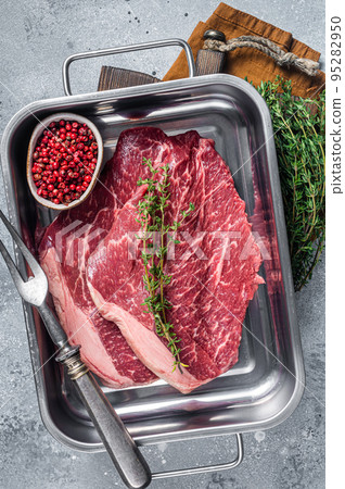 Raw thin marbled beef steak with spices in kitchen tray. Gray background. Top view 95282950